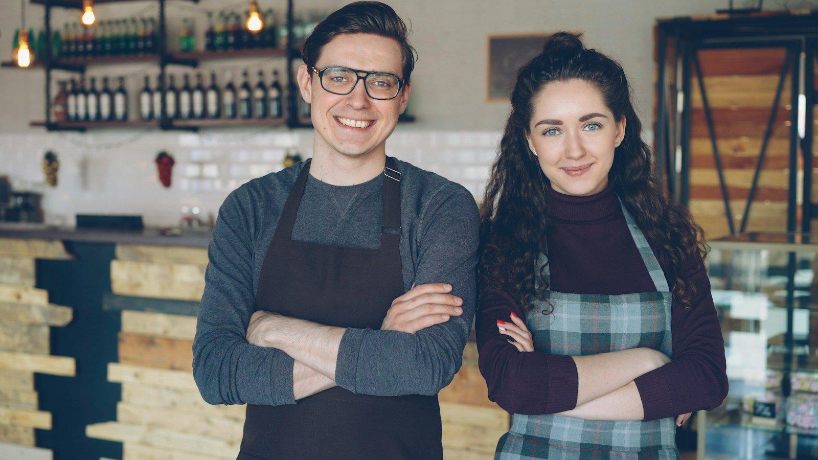 Two cafe owners standing proudly behind their counter.