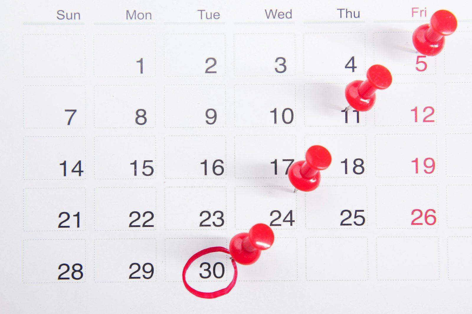 A calendar and planner on a desk with a date marked.