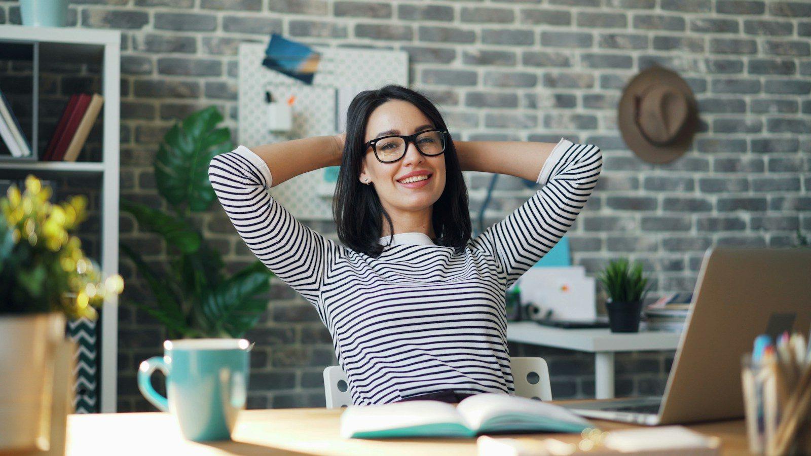 A business owner leaning back at her desk, relaxed, laptop open.